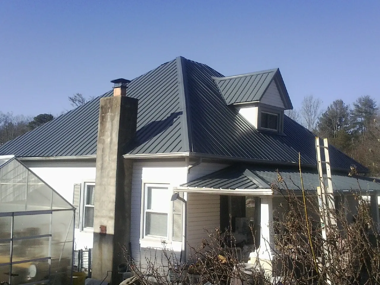 Dark blue standing seam metal roof on a white farmhouse with dormer — Slate & Tile Roof Repair by Roofing Brothers in Dry Ridge