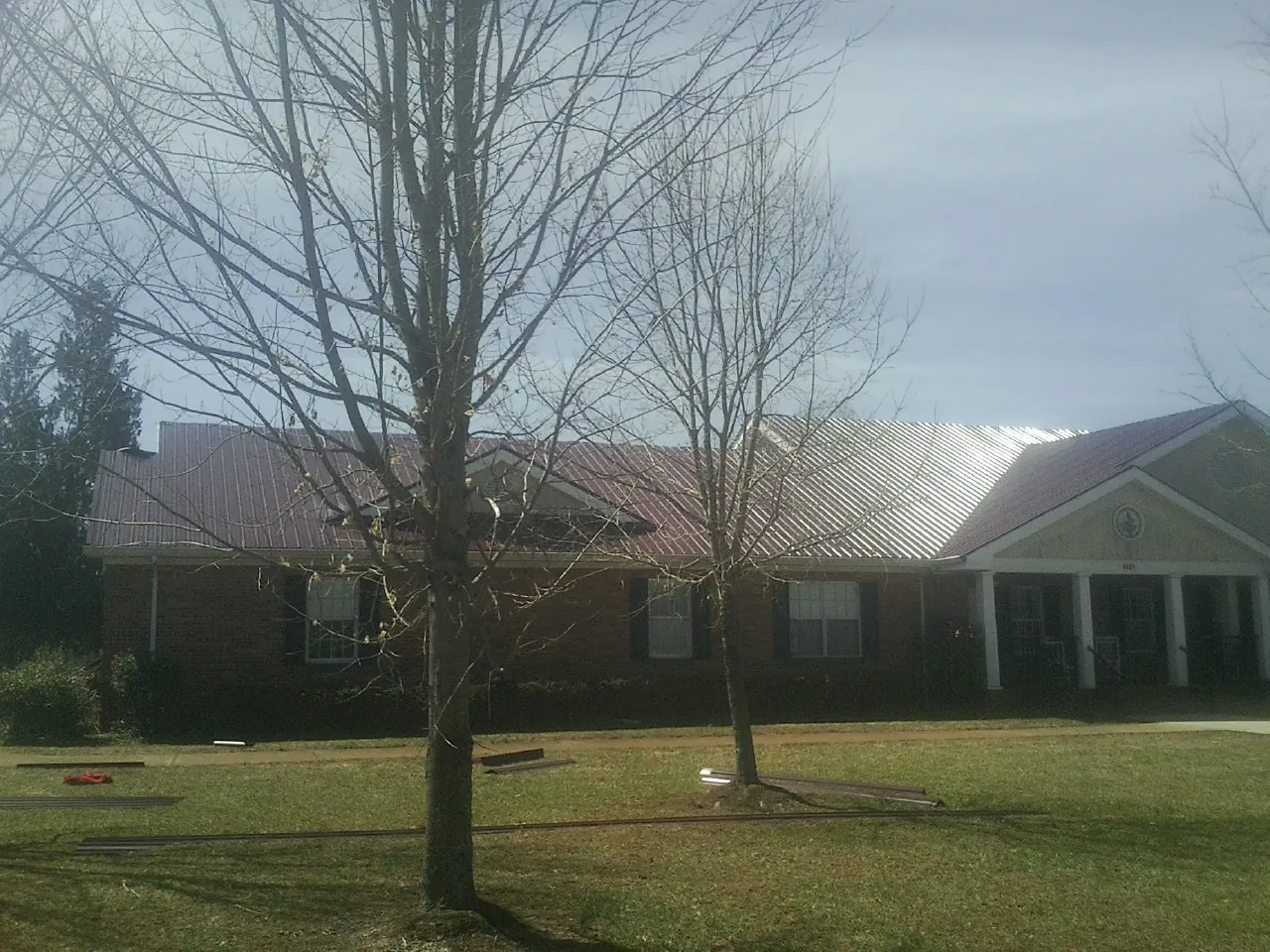 Red metal roof on a brick building seen from the front lawn in Dry Ridge