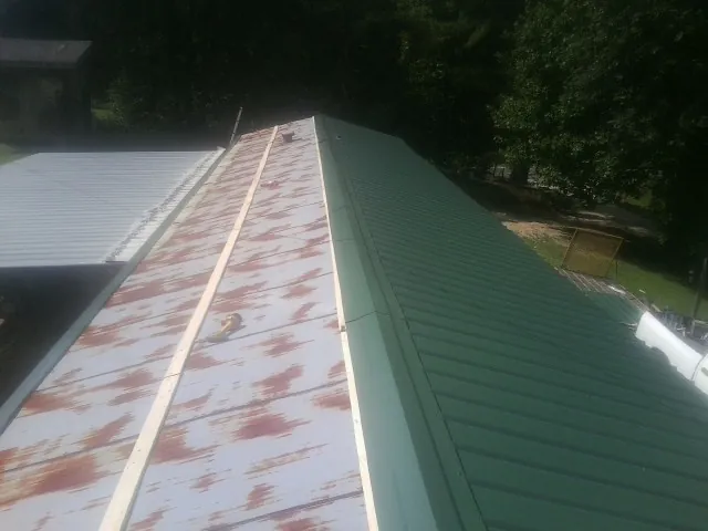 Old rusted panels beside newly installed green metal roofing — Wind Damage Roof Repair by Roofing Brothers in Dry Ridge