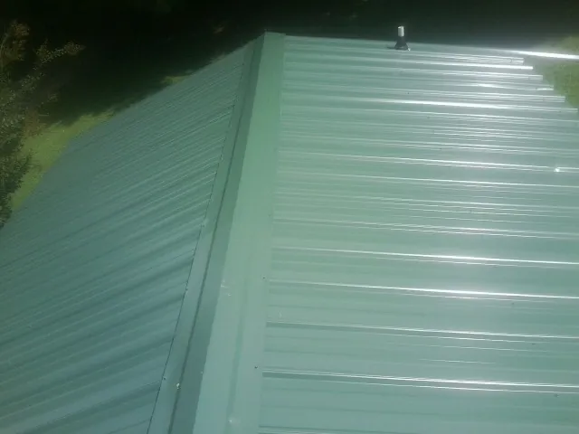 New green metal panels meeting at the ridge of a roof — Flat Roof Repair work by our crew in Dry Ridge