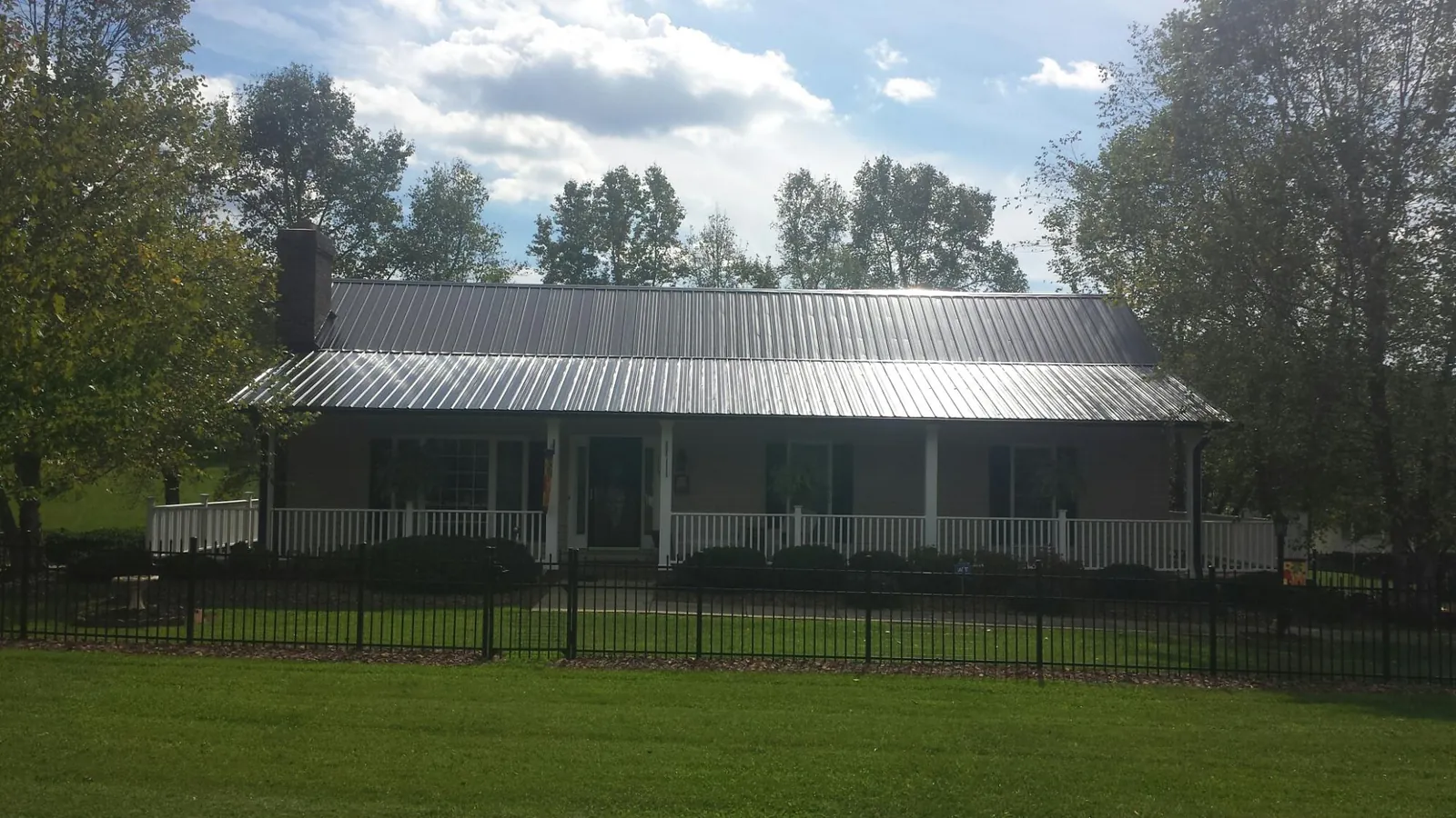 Gray metal roof on a brick ranch with a full width front porch — Gutter Guard Installation work by our crew in Dry Ridge