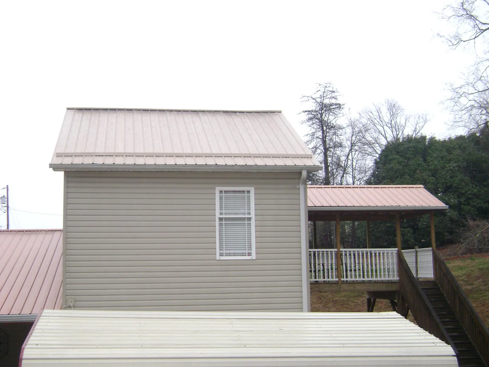 Tan metal roofs on a two story addition and attached porch, from a Roof Replacement job in Dry Ridge