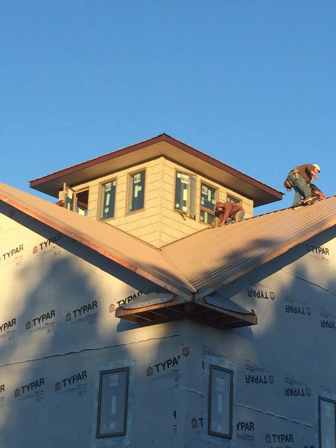 Roofers working around a rooftop cupola on a new metal roof at sunset — Roof Waterproofing in Dry Ridge by Roofing Brothers
